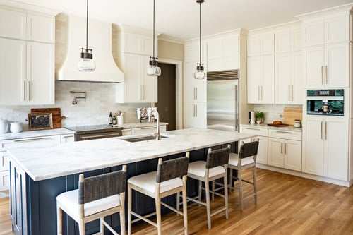 Transitional kitchen design with marble island and dual-tone cabinetry in Fayetteville, GA custom home by Exodus Design Build.