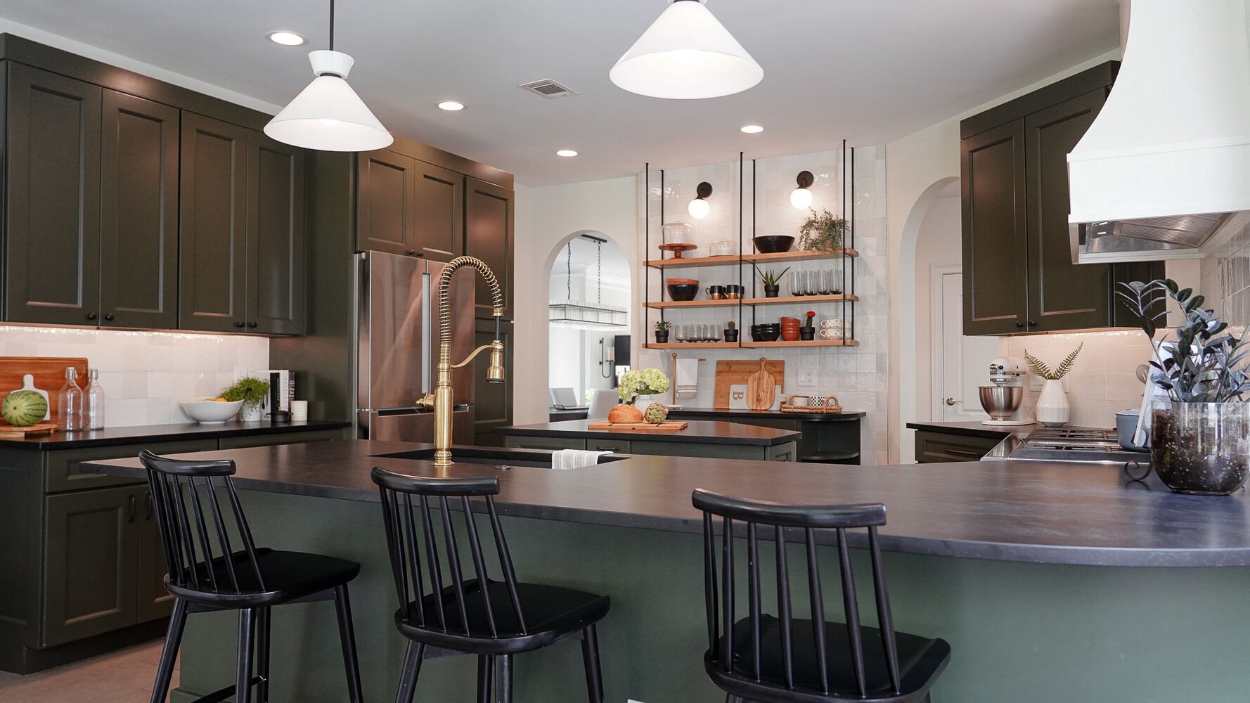 Full kitchen view with brass faucet and black bar stools in an Auburn, GA custom home by Exodus Design Build.