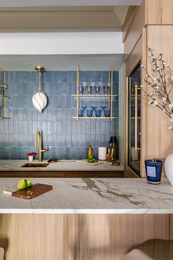 Corner view of custom bar showcasing blue glassware and gold shelving by Exodus Design Build in Loganville, GA