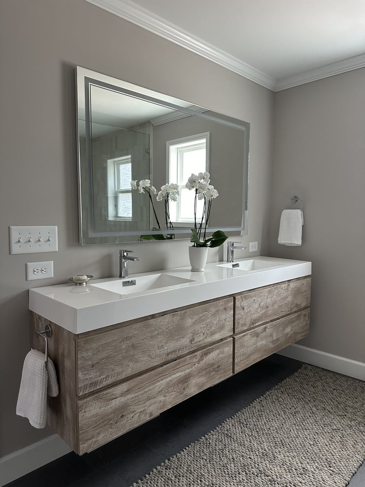 Floating wood vanity with double sinks in a custom bathroom by Exodus Design Build in Suwanee, GA.