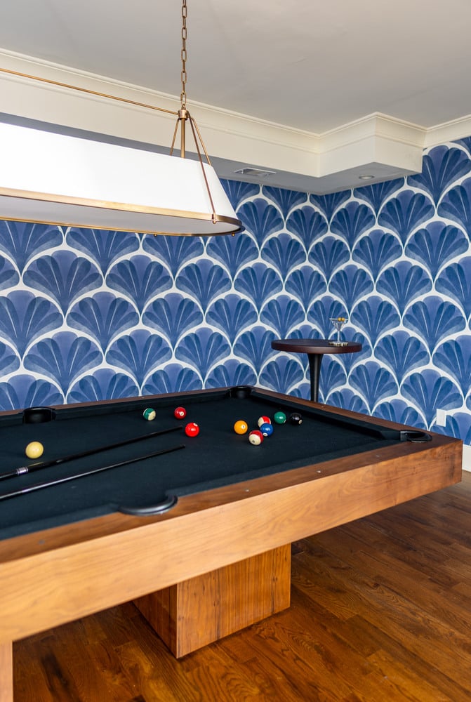 Angled view of a custom game room with pool table and wallpapered accent wall by Exodus Design Build in Braselton, GA.