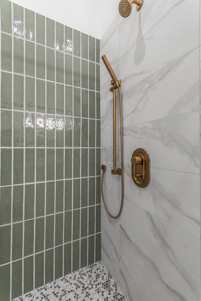Close-up of brushed gold shower hardware in Dacula, GA custom bathroom by Exodus Design Build