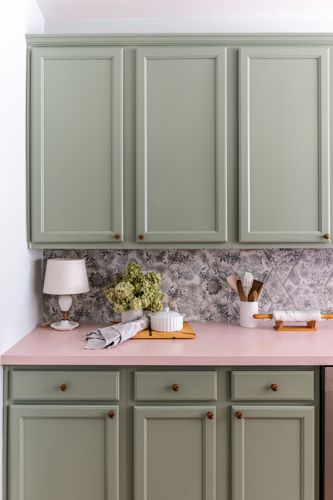 Sage green cabinetry with pink countertops and floral backsplash in a Norcross, GA custom home by Exodus Design Build.