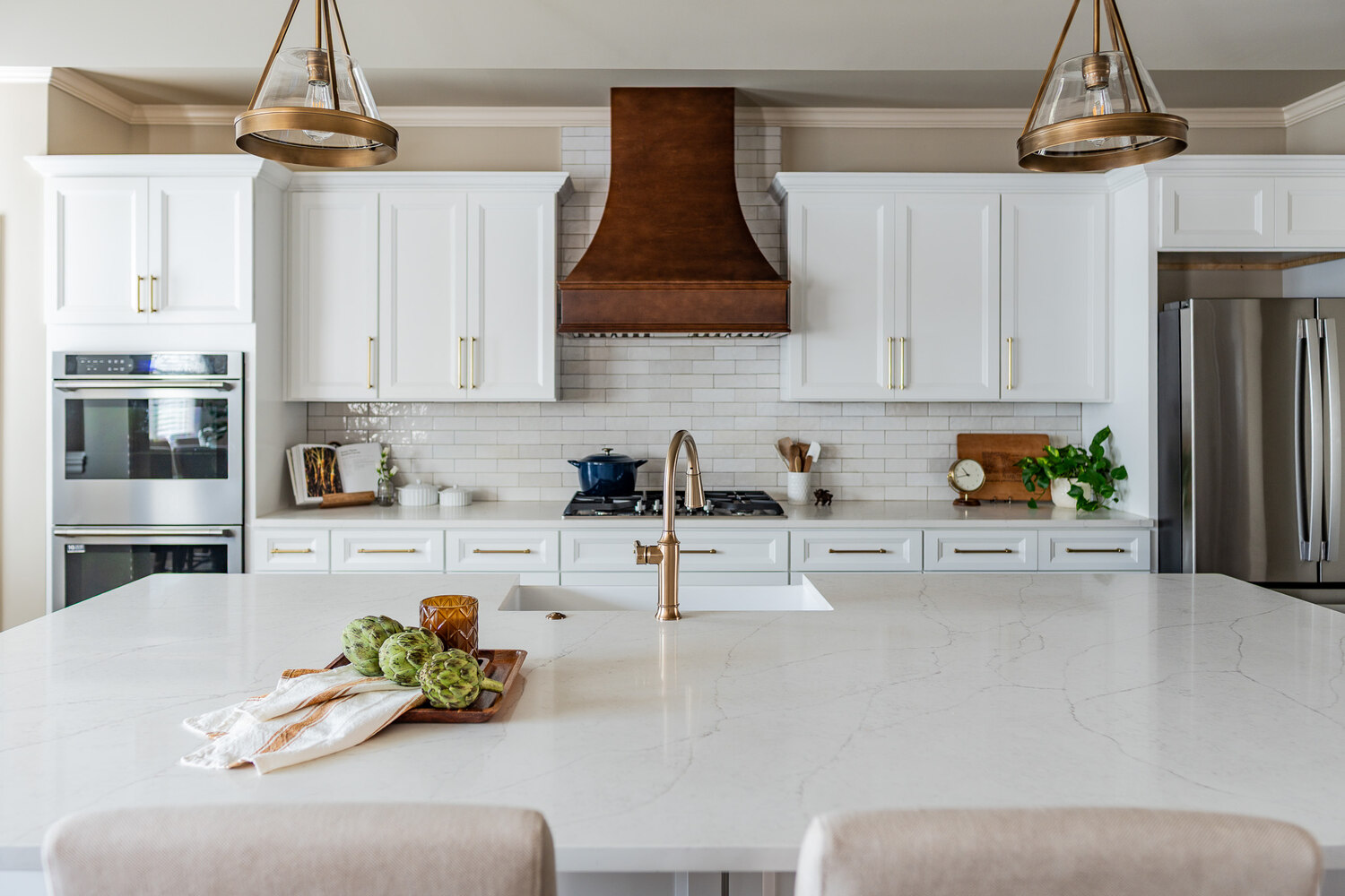 Marble island and dual pendant lights in a custom kitchen by Exodus Design Build in Berkeley Lake, GA.
